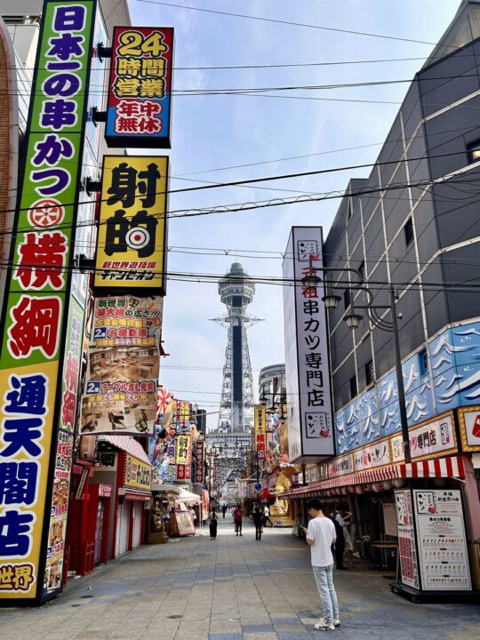 大阪・新世界の串かつ店の看板ごしに見える通天閣