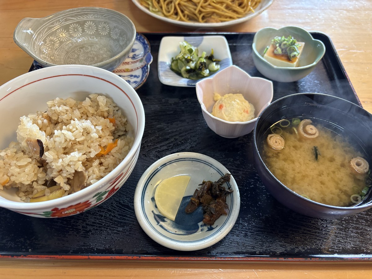 蒜山おこわと味噌汁、小鉢が並んだ膳。奥に蒜山やきそば