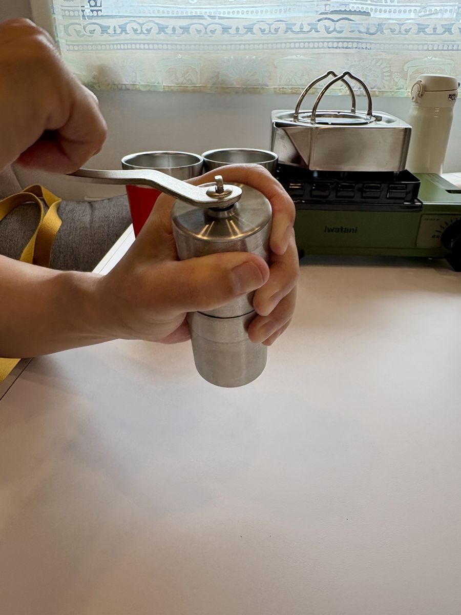 キャンピングカーの車内でコーヒー豆を手挽きミルで挽いているところ